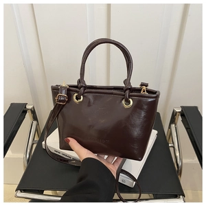Detail of glossy chocolate brown bucket bag with gold hardware and fashion embossing
