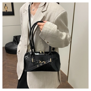 Detailed close-up of glossy black leather bag with gold buckle and fashion hardware