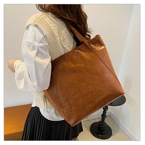 Brown crocodile pattern tote bag shown over shoulder with high-quality leather texture