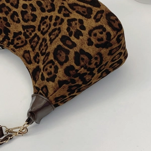 Detail of leopard print faux fur texture with dark brown leather piping and gold metal hook