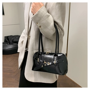Macro shot of black patent leather bag with gold hardware and embossed fashion text