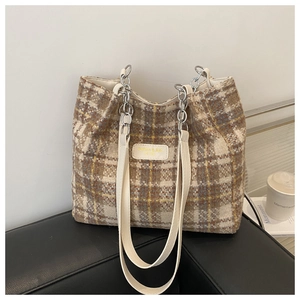 Detail of plaid tote bag with brown checkered fabric and stylish metal chain strap
