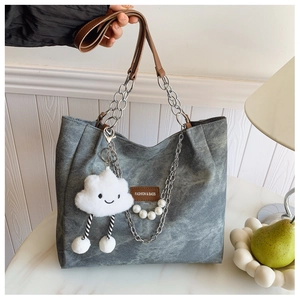 Detail of grey denim tote bag with brown handles, pearl chain and cloud plush charm