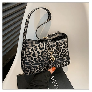 Detail view of leopard print baguette bag featuring a gold lobster clasp and textured strap