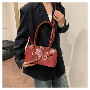 Detail of burgundy glossy leather bag with gold hardware and long shoulder handles