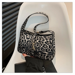 Detail of black and white leopard print shoulder bag with gold metal buckle on white seat