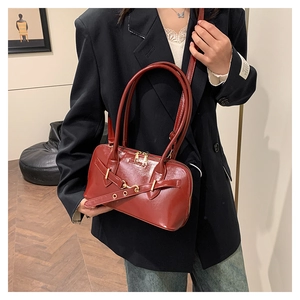 Detail of dark red patent leather Boston bag with gold hardware and fashion buckle strap