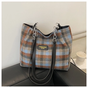 Close-up of the vintage plaid wool fabric and leather logo tag on the chain tote bag