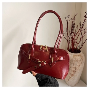 Detail of burgundy patent leather underarm bag featuring embossed FASHION text