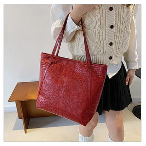 Macro view of deep red crocodile texture on large capacity faux leather tote bag