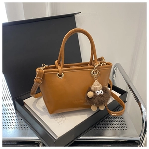 Detail der braunen Leder-Eimertasche mit Plüsch-Anhänger und Fashion-Logo-Gravur