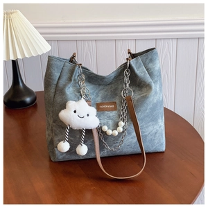 Close-up of gray textured tote bag with metal chain, pearl charm and leather straps