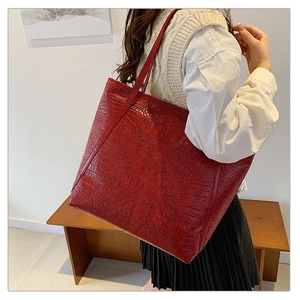 Detailed view of red crocodile pattern tote bag showing shoulder carry style and texture