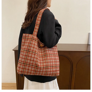 Detail of colorful plaid wool tote bag with vintage button and thick woven texture