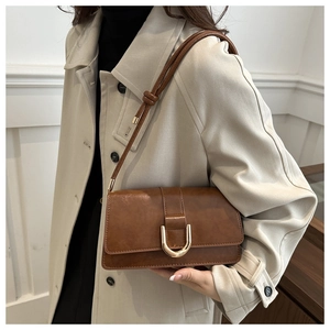 Détail du sac sous le bras en cuir marron caramel vintage avec boucle en métal doré
