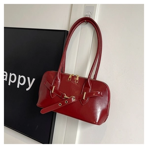 Close-up of wine red shell bag showing glossy wrinkled texture and gold hardware details