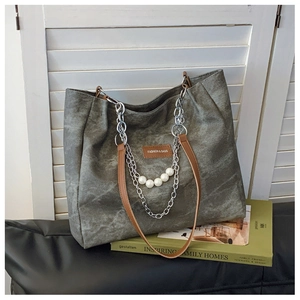 Detail of gray tote bag featuring silver chain, white pearls, and brown leather straps