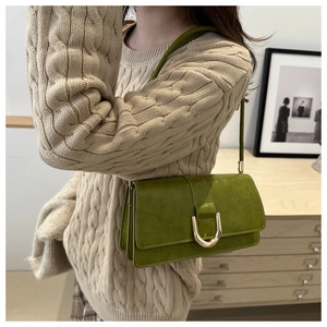 Detail of matcha green retro underarm bag with gold U-shaped buckle on beige sweater