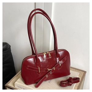 Detail of burgundy glossy tote bag featuring gold zippers and adjustable shoulder strap