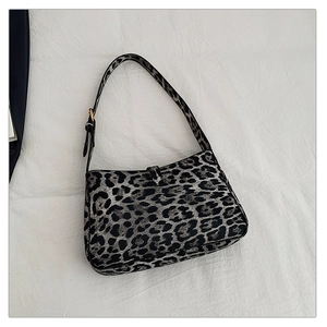 Detail shot of leopard print hobo bag with adjustable strap on white fabric background