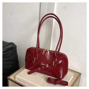 Detail view of deep red shell bag with FASHION lettering and gold metal zipper hardware