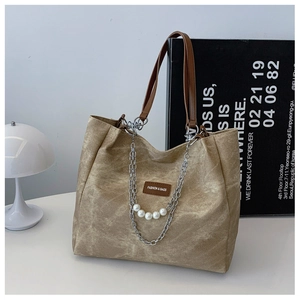Detail of vintage khaki tote bag with pearl chain decoration and fashion brand label