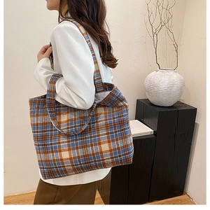 Detail view of large tweed plaid tote bag in blue and orange on a female model