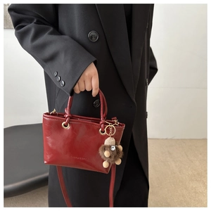 Detail der dunkelroten Leder-Eimertasche mit abnehmbarem Gurt und schickem Plüsch-Anhänger