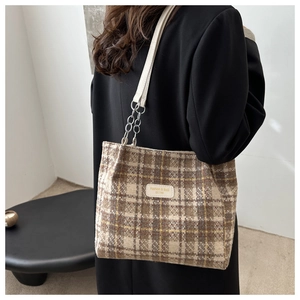 Detail of plaid tote bag featuring thick wool fabric and leather chain strap in room