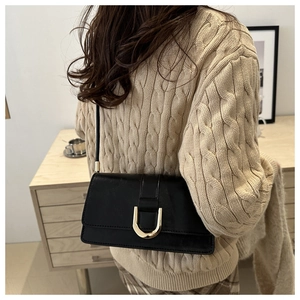 Détail du sac bandoulière en similicuir noir avec une boucle fer à cheval dorée