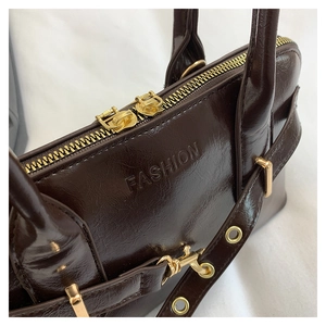 Detail of dark brown glossy leather texture and golden hardware on the vintage tote bag
