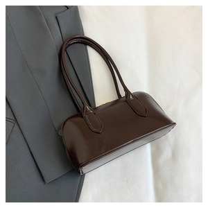 Detail of vintage dark brown faux leather shoulder bag on grey suit and white background