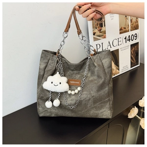 Detail showing grey canvas tote bag with chain strap and plush cloud pendant charm