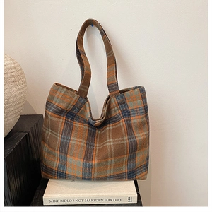 Detail of checkered plaid wool tote bag showing thick fabric texture and button closure
