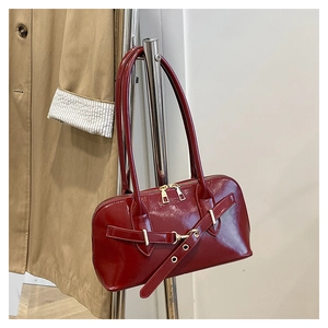 Close-up of glossy burgundy patent leather shoulder bag with fashion embossing