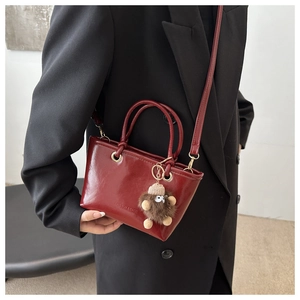 Detail der weinroten Lackleder-Beuteltasche mit Plüsch-Anhänger und Mode-Prägung