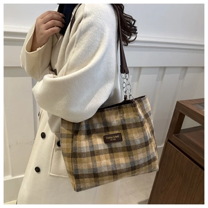Détail du sac cabas à carreaux avec écusson logo en cuir et bandoulière en chaîne