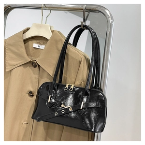 Detail of black glossy shoulder bag with dual zippers and decorative belt buckle