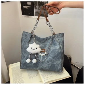 Detail of blue-grey canvas tote with leather chain strap and cloud plush charm