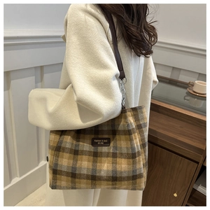 Detail of crossbody bucket bag with yellow-brown plaid pattern and metal chain strap
