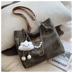 Detail of grey-green tote bag with pearl chain and smiling cloud plush charm