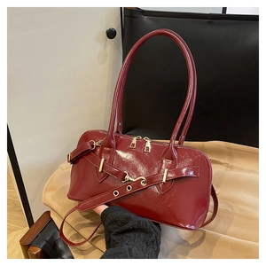 Detail of burgundy patent leather handbag with gold metal buckles and glossy texture
