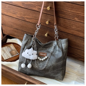 Detail of dark gray canvas tote with pearl chain and plush cloud charm on vintage wood