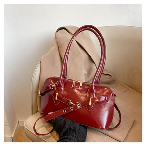 Detail of burgundy glossy leather handbag with gold metal eyelets and fashion embossing