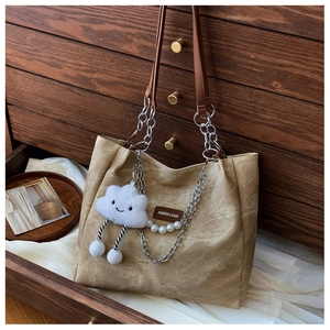 Detail of khaki tote bag with metal chain, leather tag and cute cloud pendant