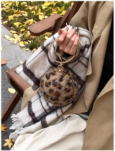 Detail einer kugelförmigen Handtasche mit Leopardenmuster und goldenem runden Metallgriff