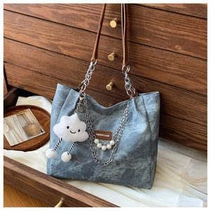 Close-up of grey denim tote bag with silver chain, pearl beads, and cloud pendant