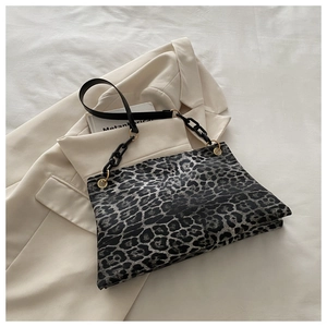 Detail van luipaardprint schoudertas met zwarte acryl ketting op een beige blazer