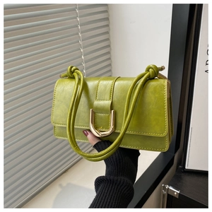 Close-up of avocado green leather bag featuring a gold horseshoe buckle and knotted strap
