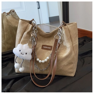Detail of khaki canvas tote bag with leather handles, pearl chain, and plush cloud charm